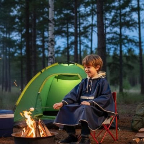 Poncho enfant garçon assis près d'un feu avec guimauve