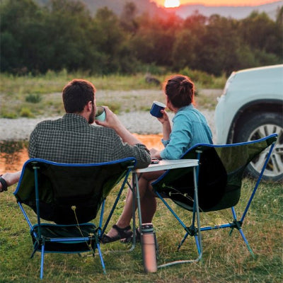 Couple sur chaise de camping devant un coucher de soleil