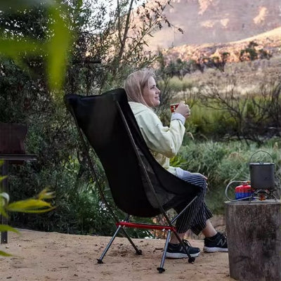 Femme avec café sur Chaise de camping admirant le paysage montagneux