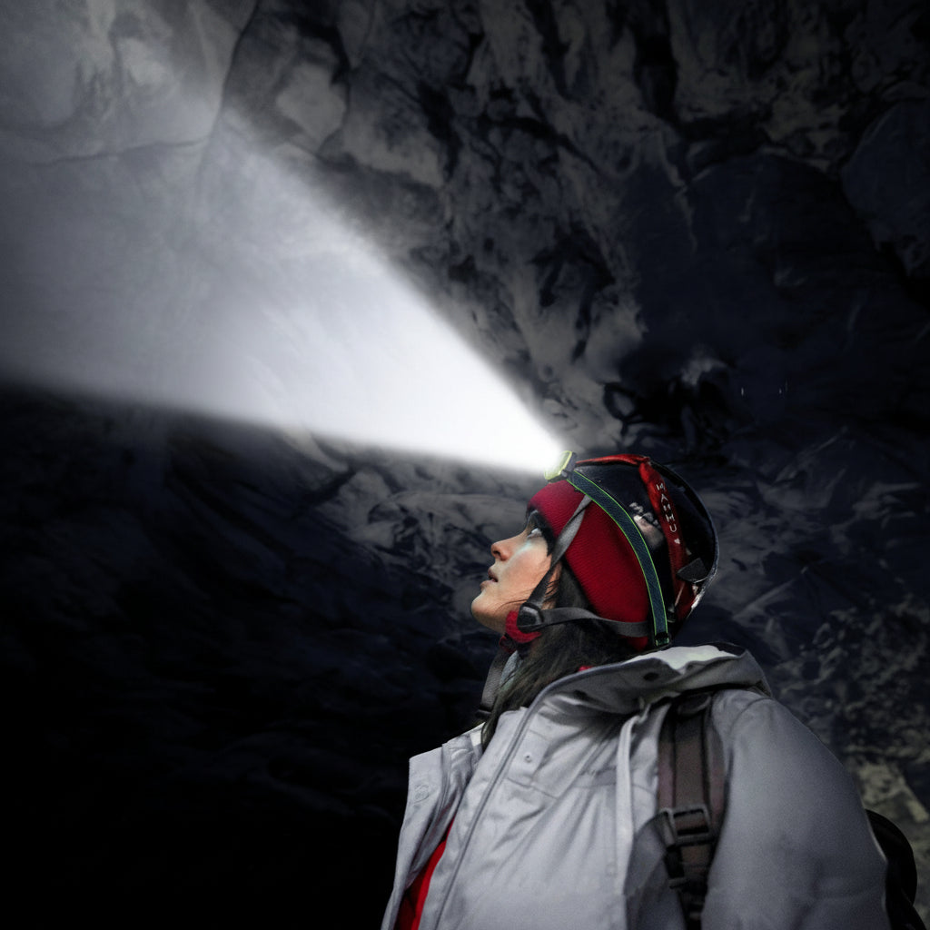femme avec lampe frontale explorant une grotte