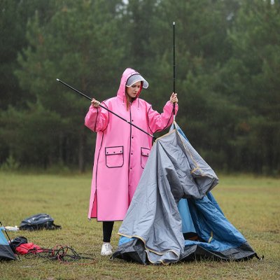 femme avec Poncho pluie rose installant tente 