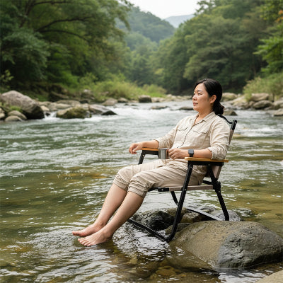 Femme relaxe sur chaise de camping pied dans ruisseau