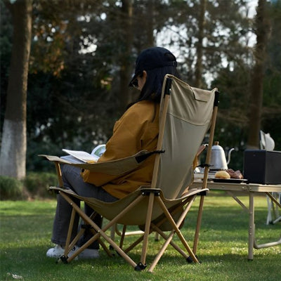 femme sur chaise de camping dans un camping avec livre
