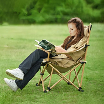 Femme sur chaise de camping beige fait lecture dans parc