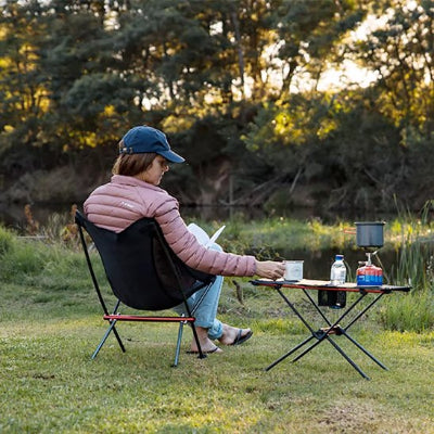 Femme sur chaise de camping relaxant avec un livre et son café 