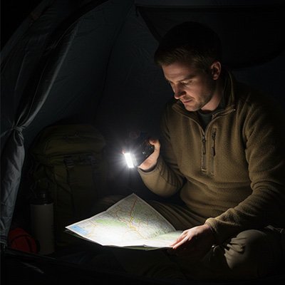 Homme avec Lampe de poche lisant sa carte 