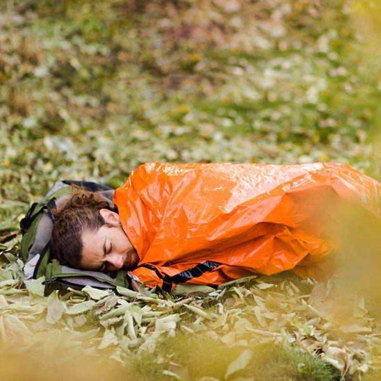 homme dans Sac de couchage grand froid sur de l'herbe  