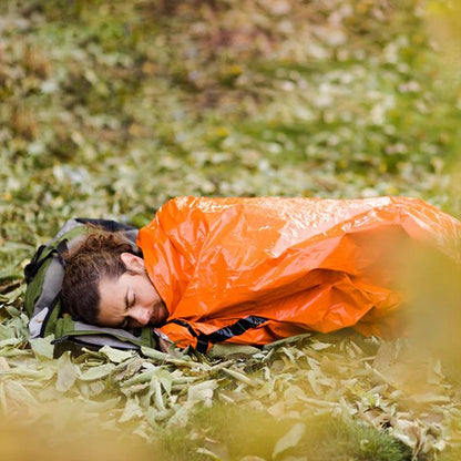homme dans Sac de couchage grand froid sur de l'herbe  