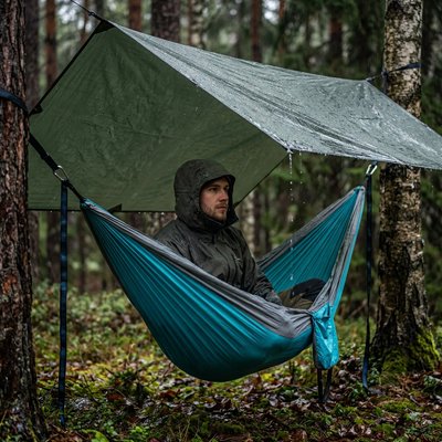 Homme sous la pluie dans son Hamac suspendu bleu